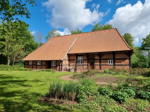 Ziegelhaus mit Fachwerk, grüne Wiese und Nutzgarten