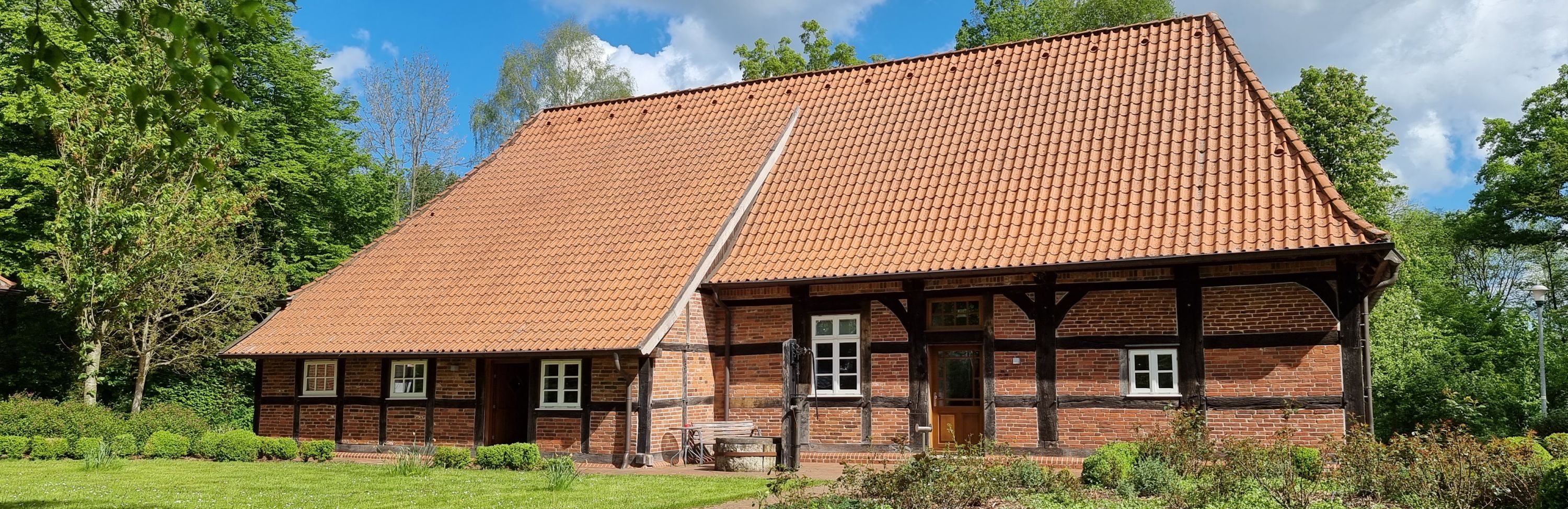Ziegelhaus mit Fachwerk, grüne Wiese und Nutzgarten
