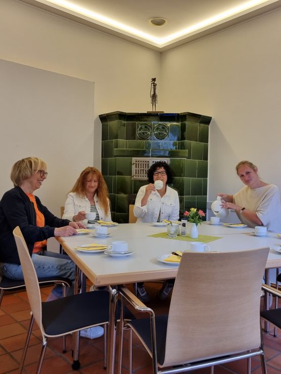 Speiseraum mit Kamin. Am Tisch sitzen vier Frauen und trinken Kaffee.